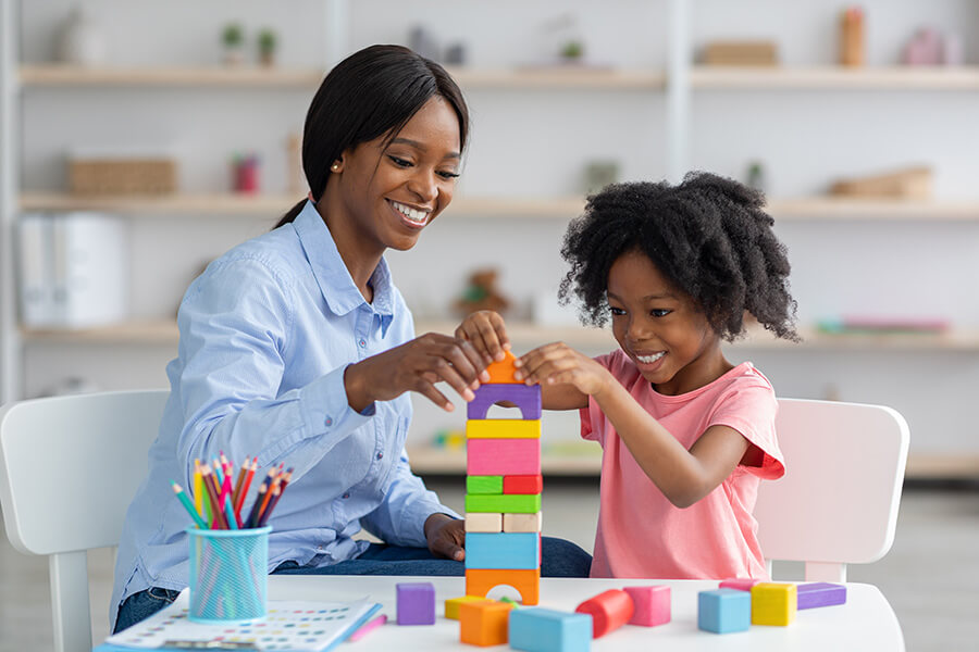 woman building blocks with a young girl